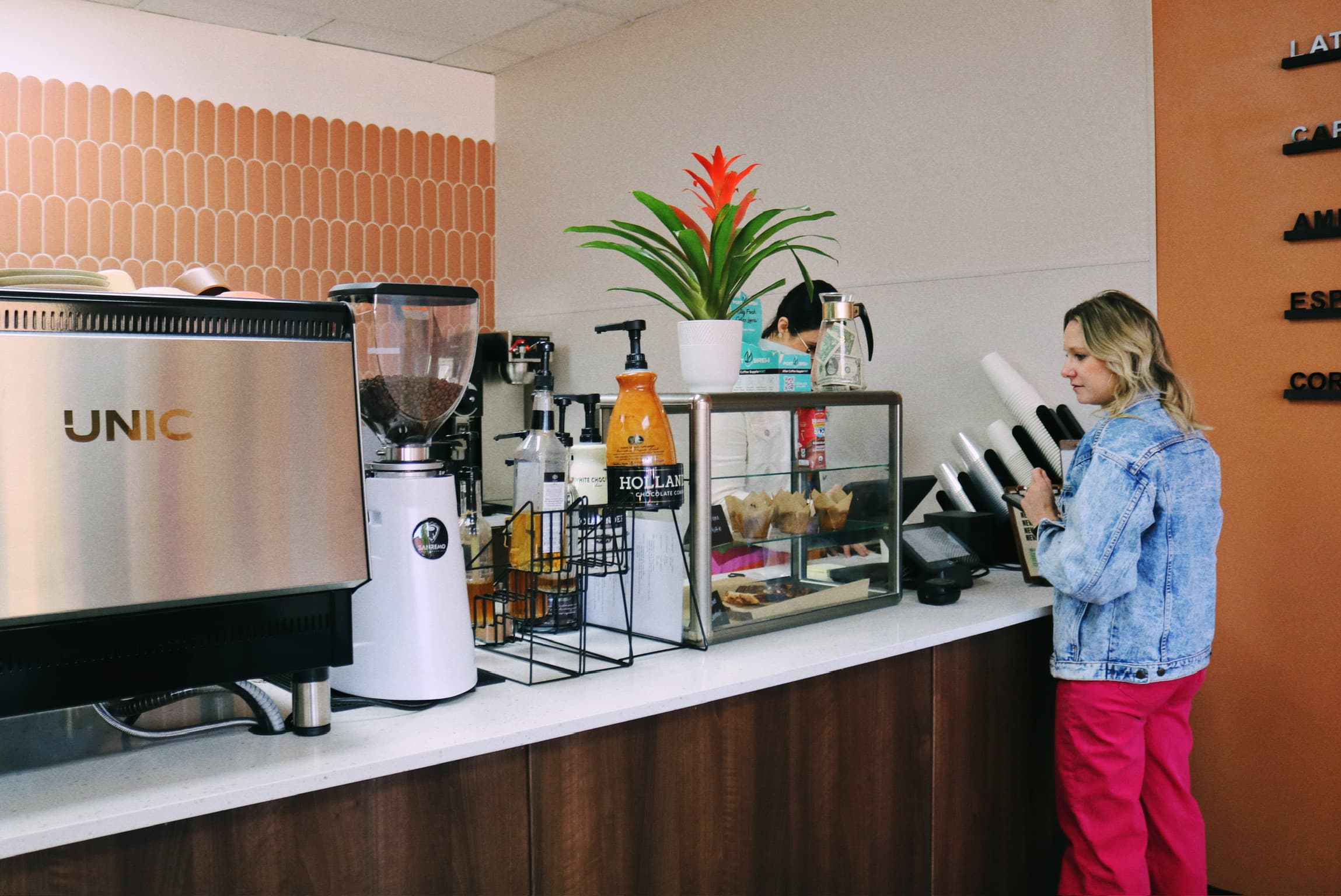 Barista preparing drinks at the espresso bar with the UNIC machine and pastry case