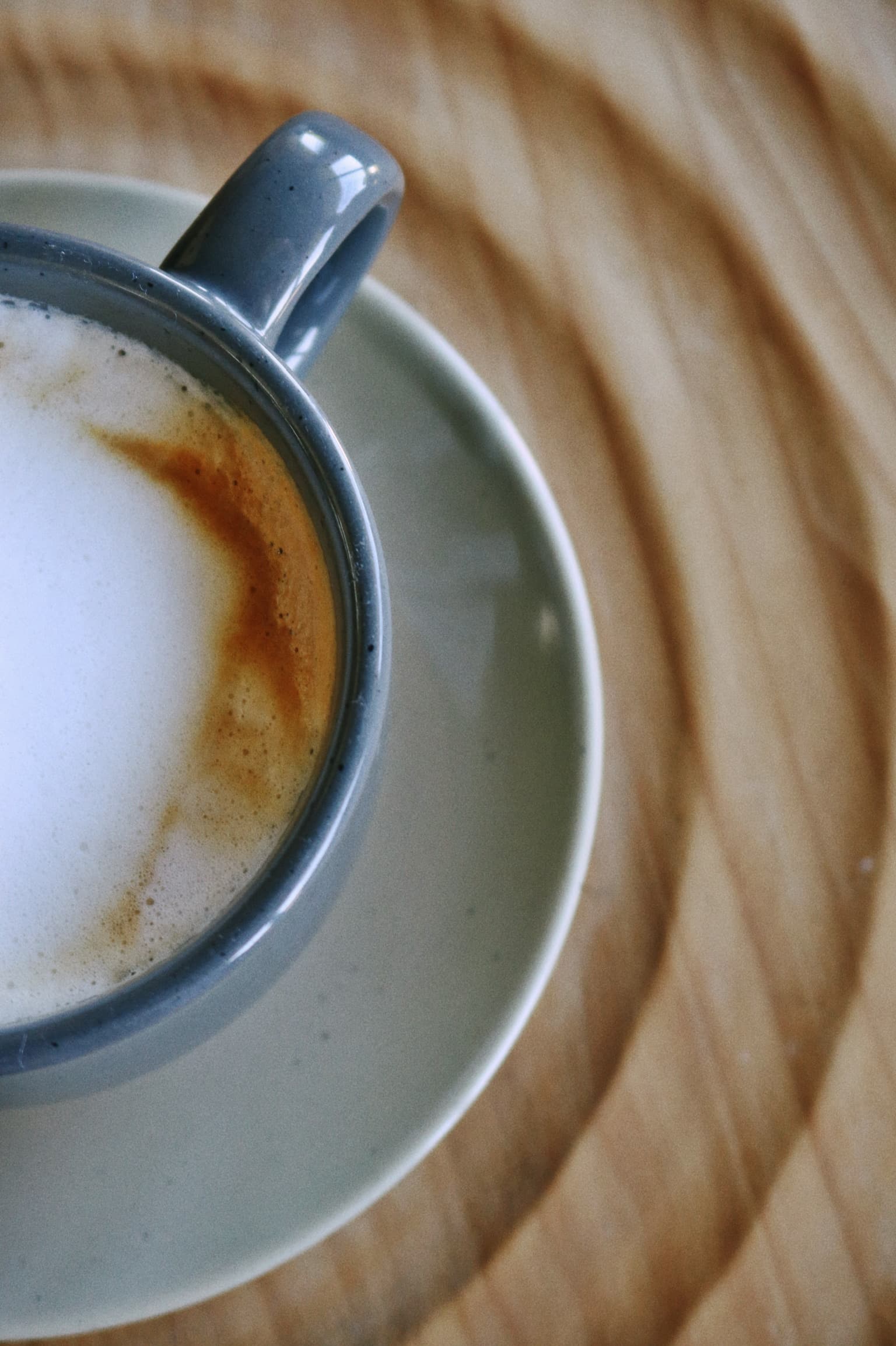Overhead close-up of a cappuccino with crema in a slate-colored cup