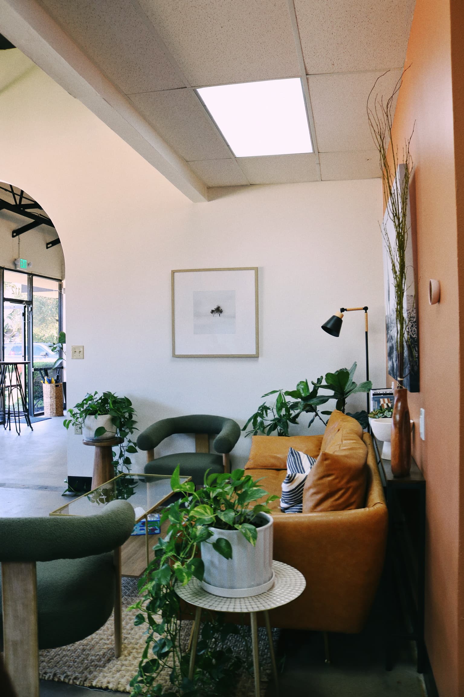 Cozy lounge corner with a leather couch, plants, and gallery-style framed art