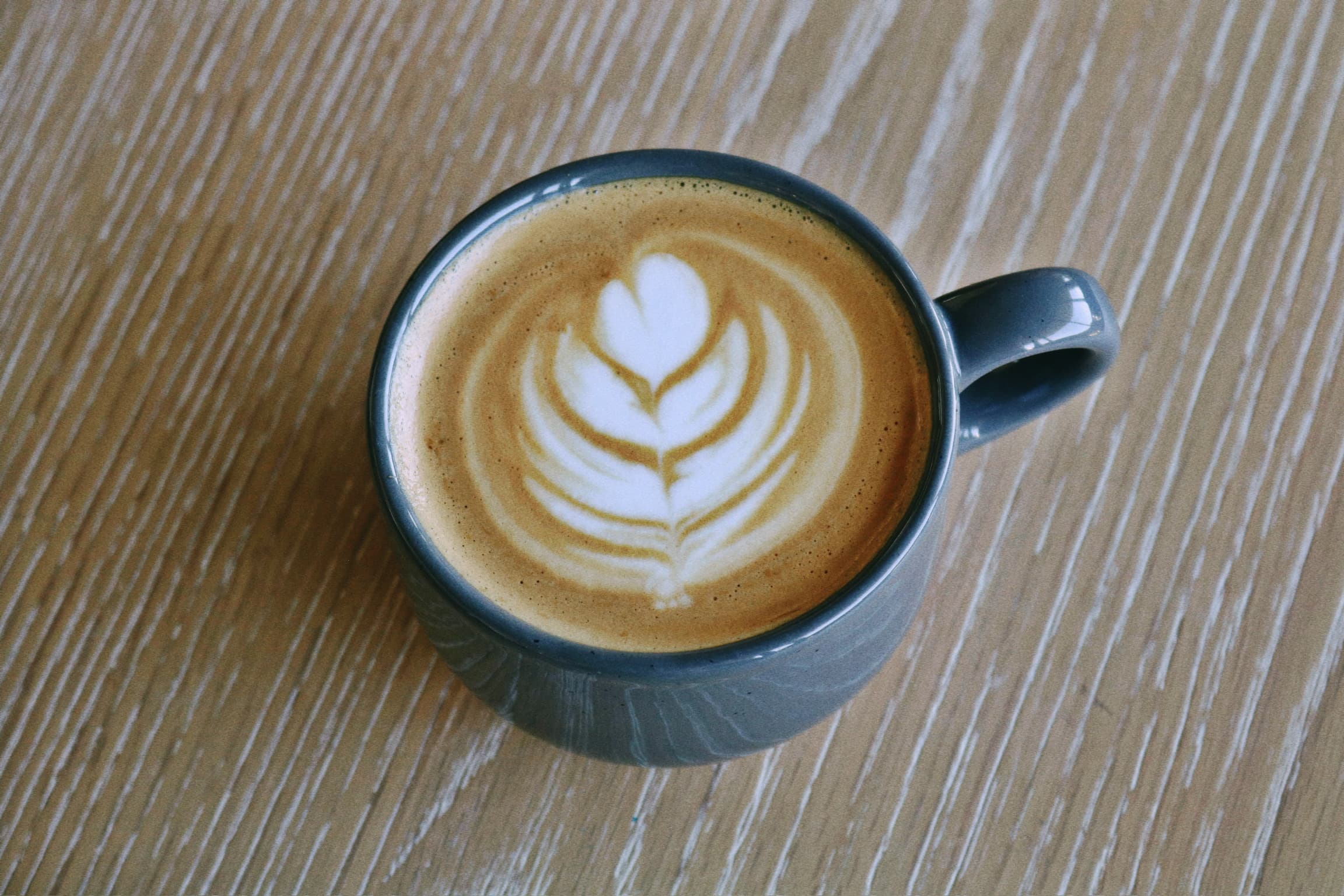 Top-down view of a latte with a tulip art pour in a slate-colored mug