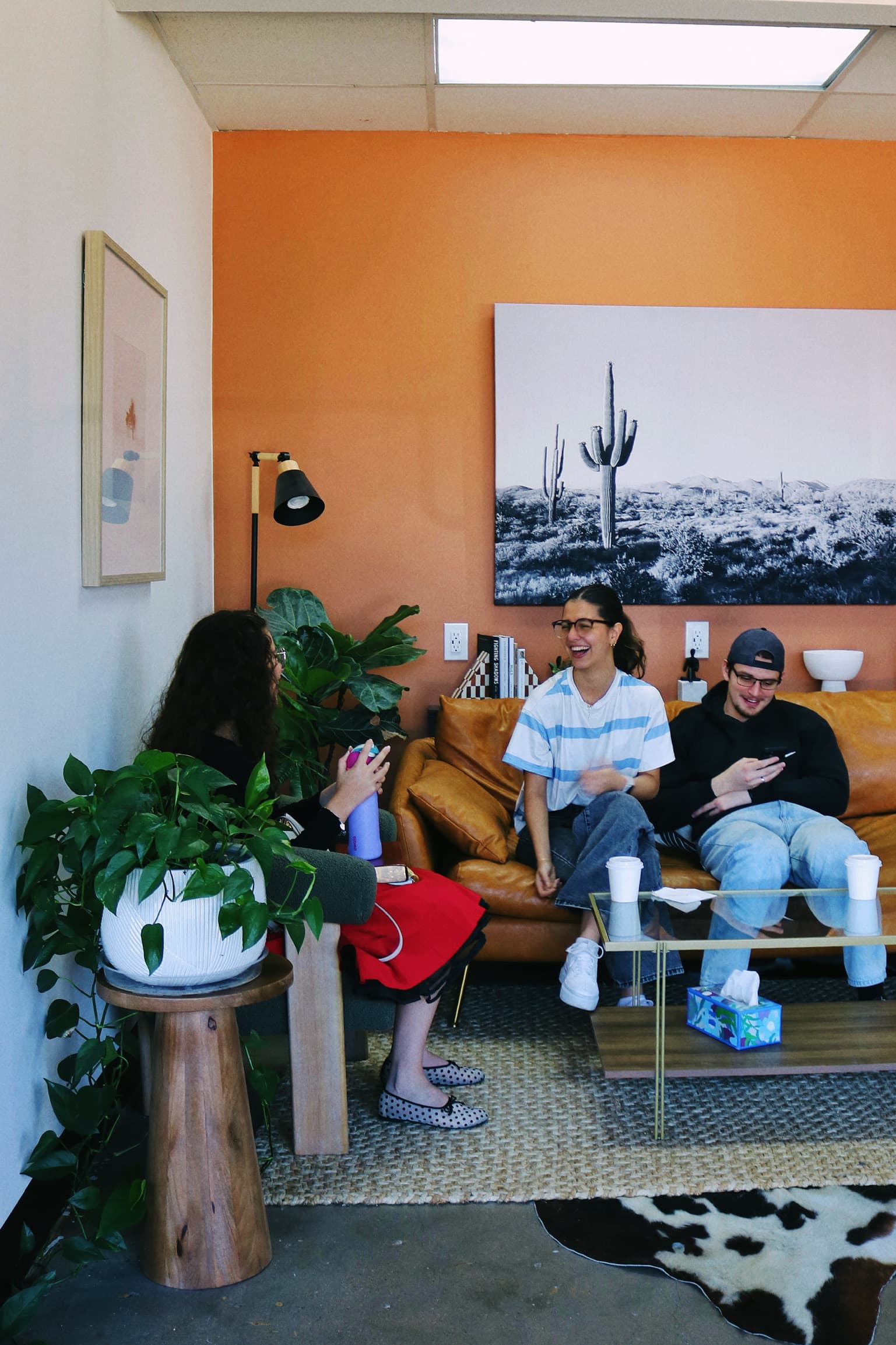 Customers chatting on a leather sofa beneath a black-and-white saguaro print